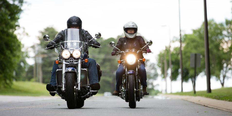 Two motorcyclists driving down the street